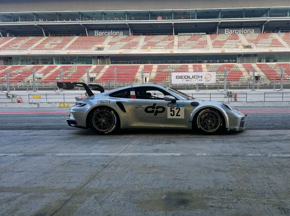 Porsche 911 GT3 Cup argent, numéro 52, livrée "dp Driving & Performance", sur la voie des stands du Circuit de Barcelona-Catalunya