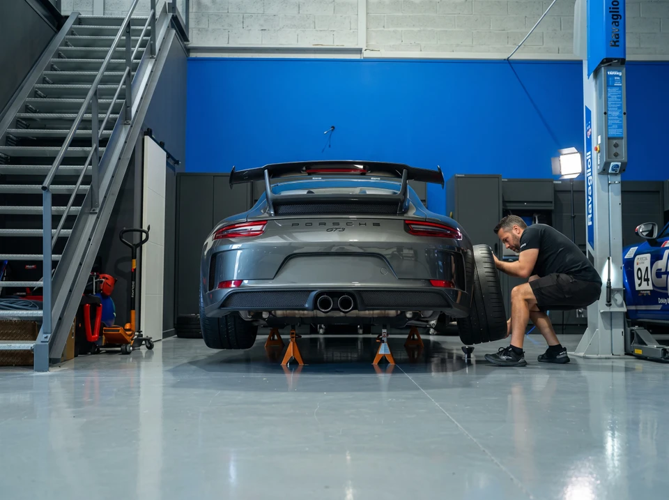 Mécanicien automobile travaillant sous un véhicule surélevé dans un garage professionnel
